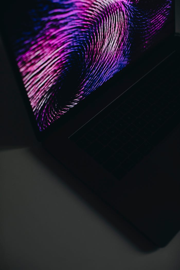 A close-up of an open laptop displaying a vibrant abstract pattern in purple and black.